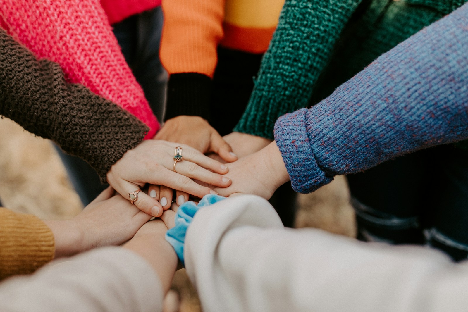 A group of people stacking their hands together outdoors